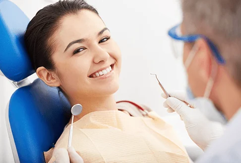 A patient smiling in the dental chair while the dentist explains her treatment